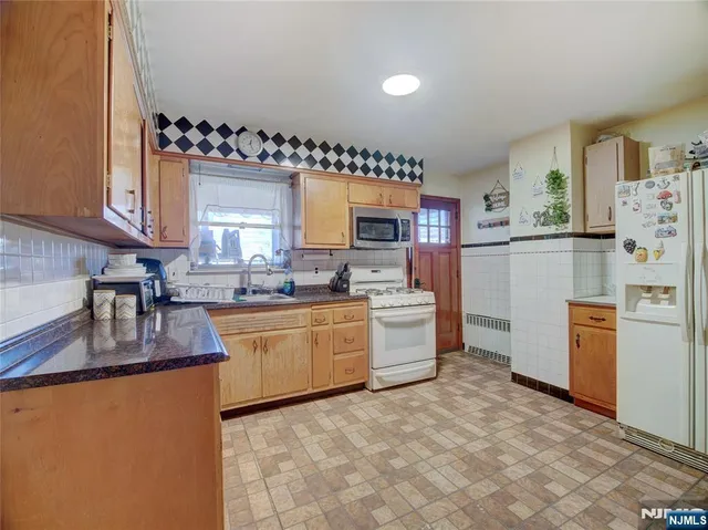 a kitchen with granite countertop stainless steel appliances a refrigerator a sink a stove a counter space and cabinets