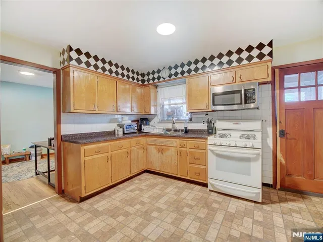 a kitchen with granite countertop a stove a sink and a refrigerator