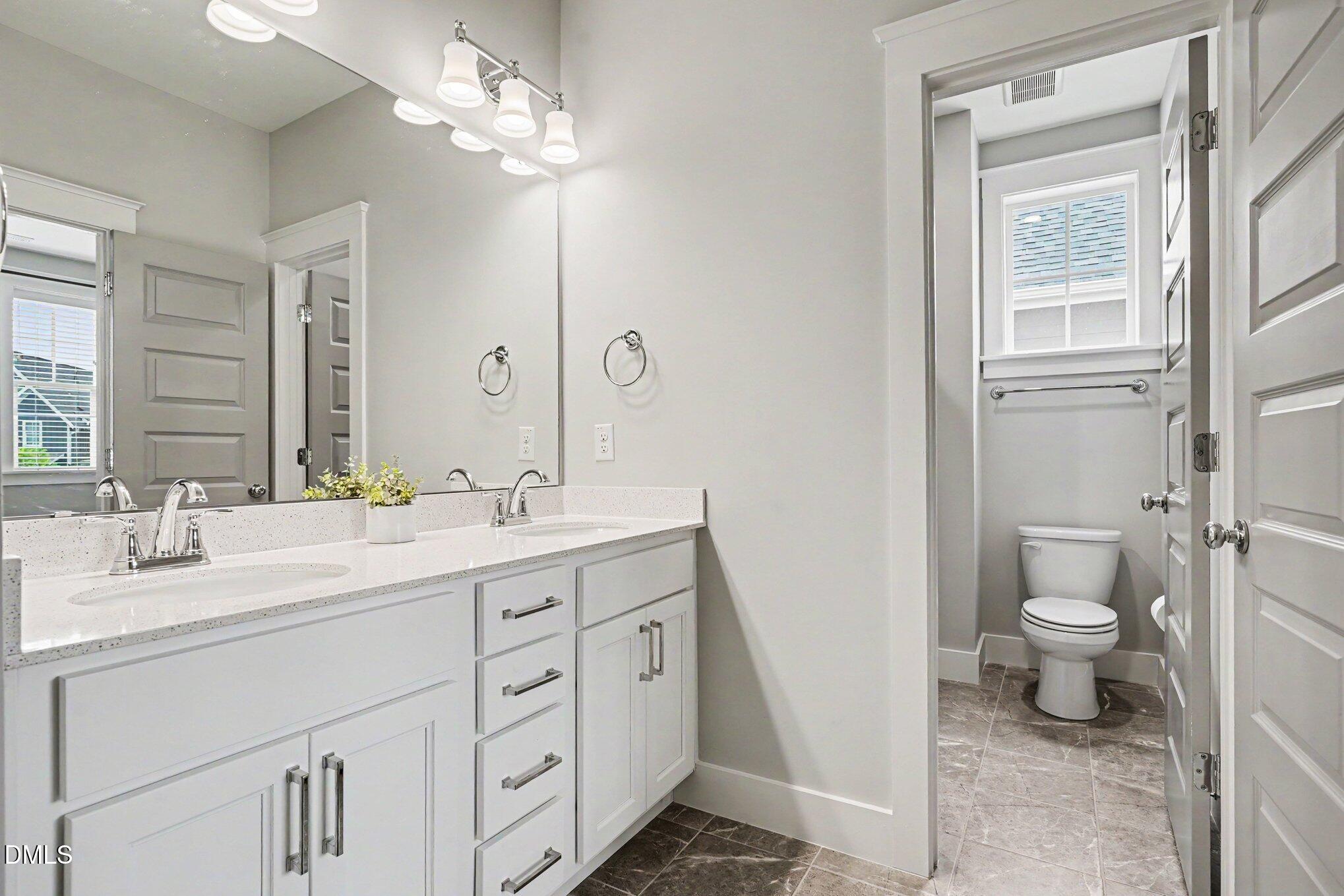 824 Watercolor Way Durham, NC 27713 - Photo 18 of 28 a spacious bathroom with a double vanity sink a mirror and a toilet