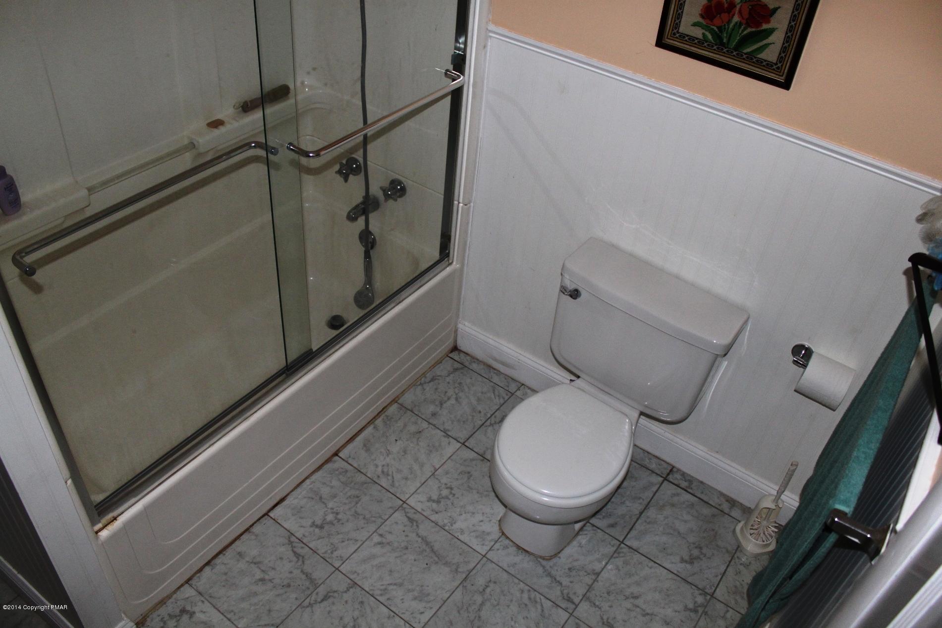 1055 Bush Road Cresco, PA 18326 - Photo 13 of 24 a white toilet sitting next to a bathroom sink and a mirror