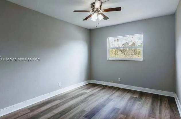 an empty room with wooden floor and ceiling fan