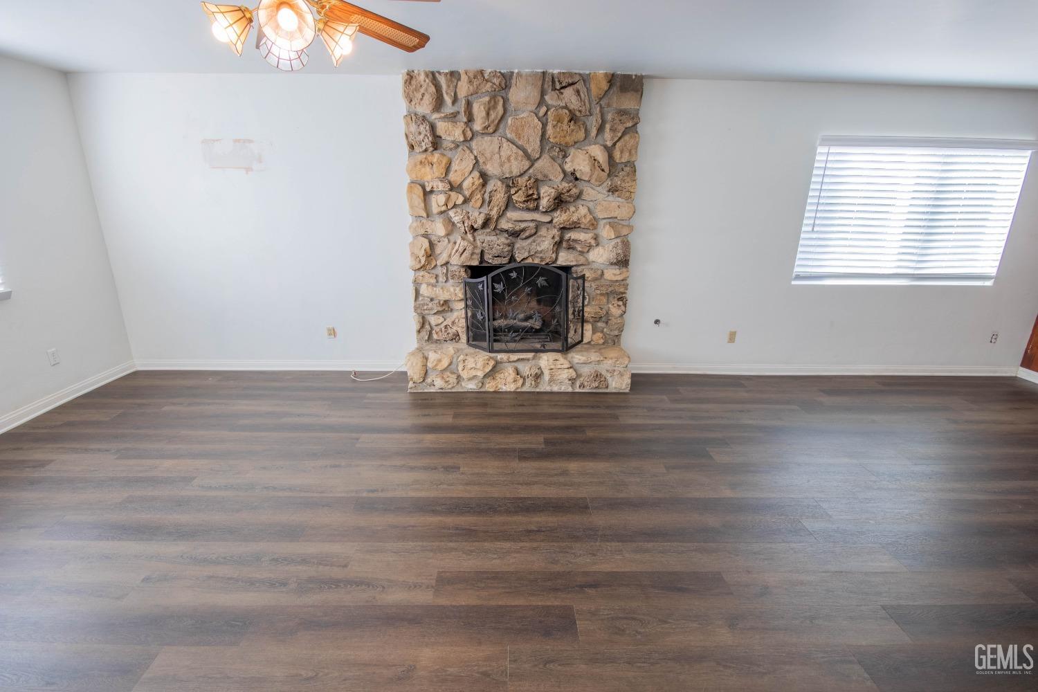 Undisclosed Address Bakersfield, CA 93309 - Photo 8 of 39 an empty room with wooden floor a fireplace and a large window