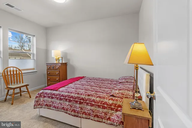 a bedroom with a bed chair and a lamp on dresser