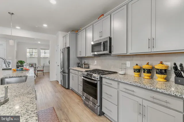 a kitchen with stainless steel appliances granite countertop a stove a sink and a refrigerator