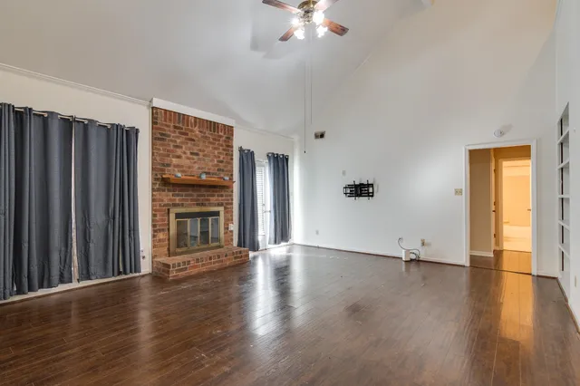 an empty room with wooden floor chandelier and windows
