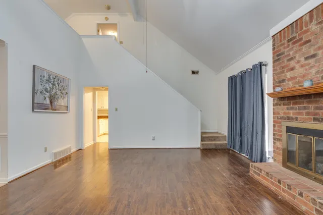 a view of empty room with wooden floor and fireplace