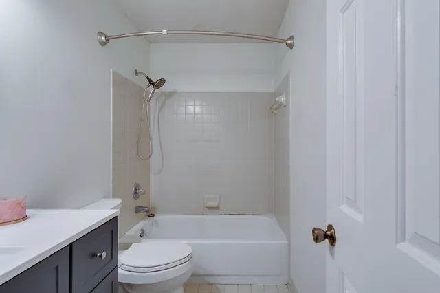 a bathroom with a granite countertop bathtub shower sink vanity and toilet