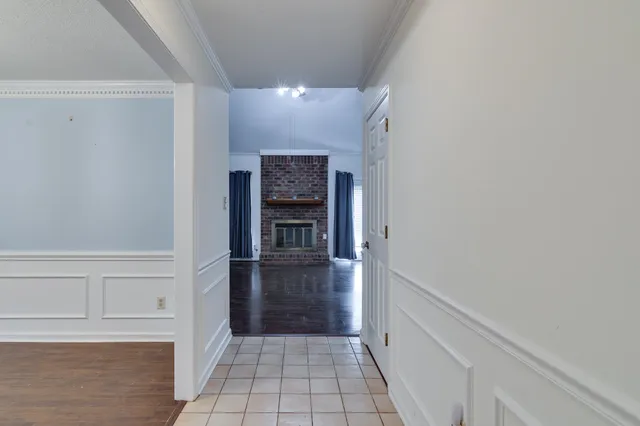 a view of hallway with an empty room and fire place
