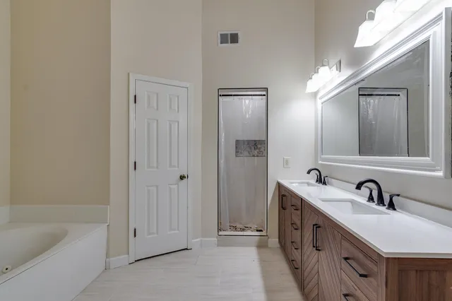 a spacious bathroom with a double vanity sink a mirror and a bathtub