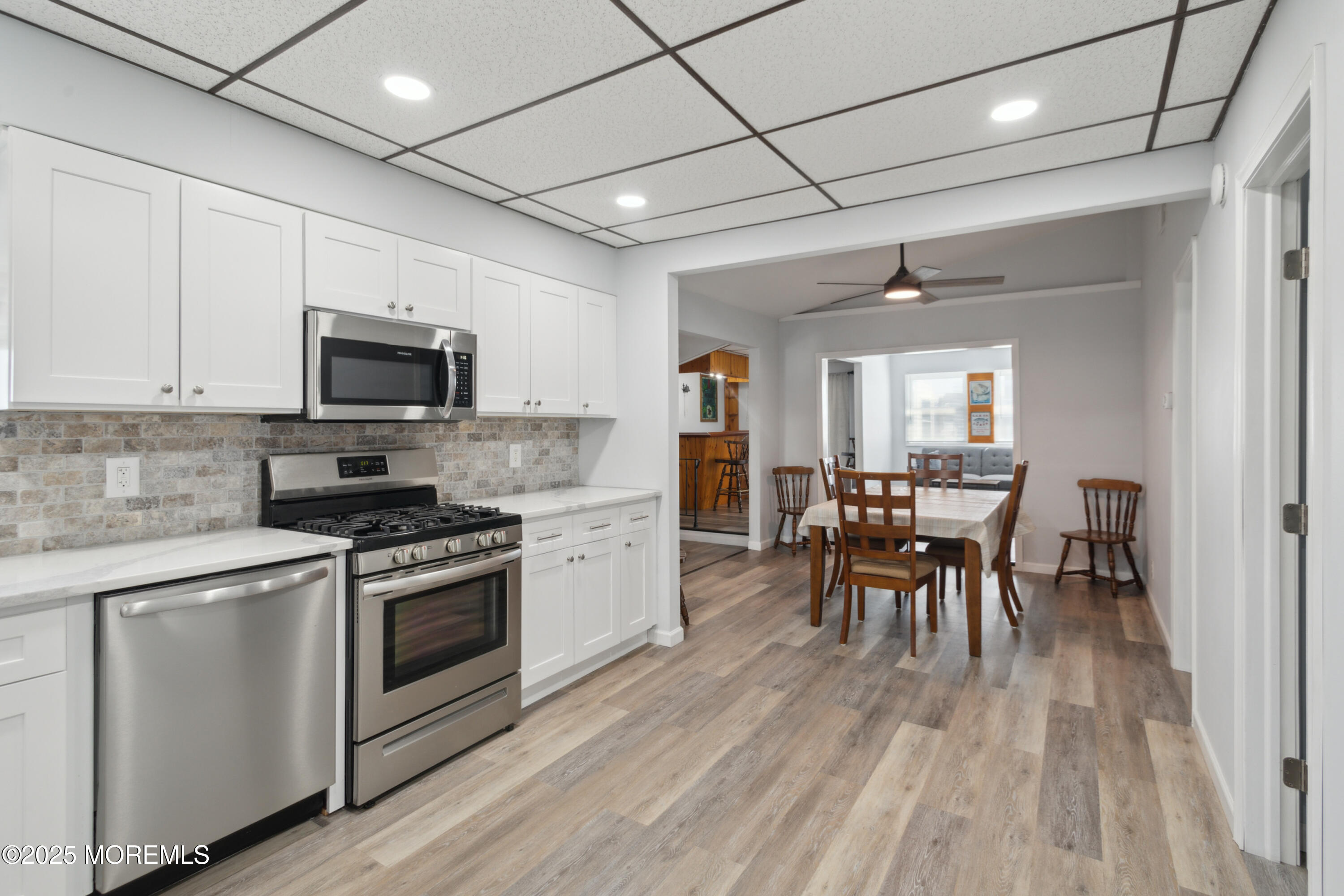 131 South Commodore Drive Little Egg Harbor, NJ 08087 - Photo 13 of 25 a kitchen with stainless steel appliances granite countertop a stove top oven a sink dishwasher a dining table and chairs with wooden floor