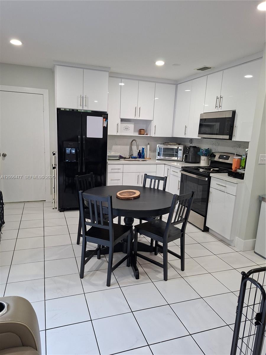 1814 Southwest 97th Terrace, Unit A Miramar, FL 33025 - Photo 4 of 9 a kitchen with stainless steel appliances granite countertop a table chairs microwave and sink