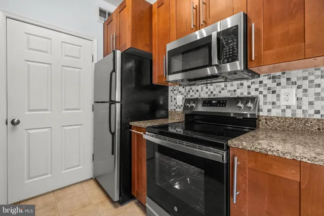 a kitchen with granite countertop cabinets stainless steel appliances and a counter top space