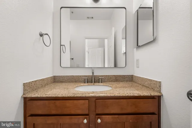 a bathroom with a granite countertop sink and a mirror