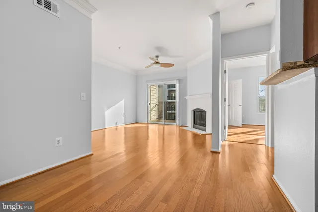a view of empty room with wooden floor and fan