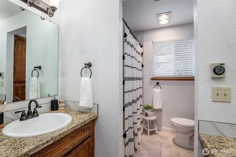 a bathroom with a granite countertop sink toilet and shower