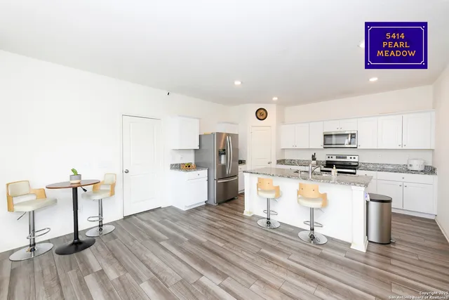 a kitchen with granite countertop a stove top oven a sink dishwasher a dining table and chairs with wooden floor