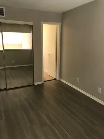 an empty room with wooden floor cabinet and windows