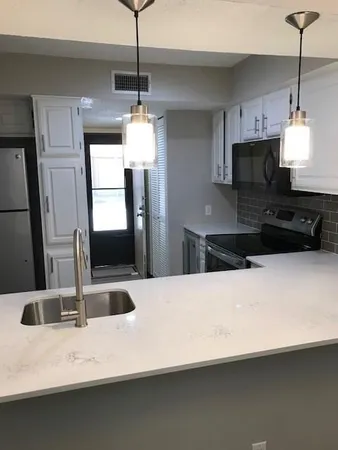 a kitchen with granite countertop a stove top oven microwave and cabinets