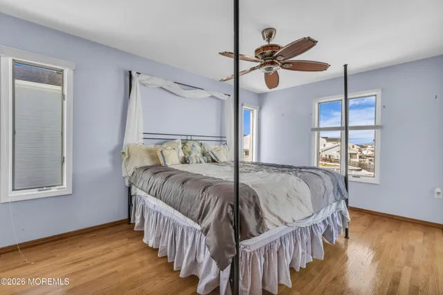a view of an empty room with wooden floor and a ceiling fan