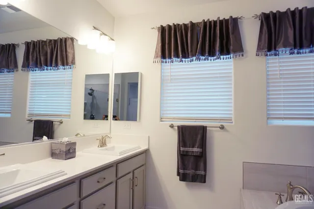 a white bath tub sitting next to a white sink and vanity
