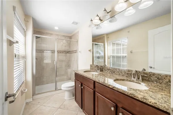 a bathroom with a granite countertop sink a toilet a mirror and shower