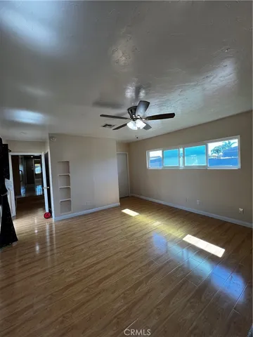 a view of an empty room with window and wooden floor