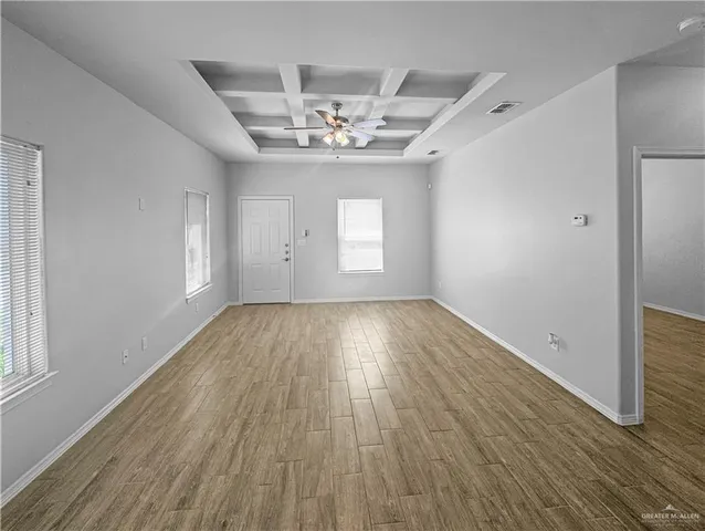 an empty room with wooden floor chandelier and windows