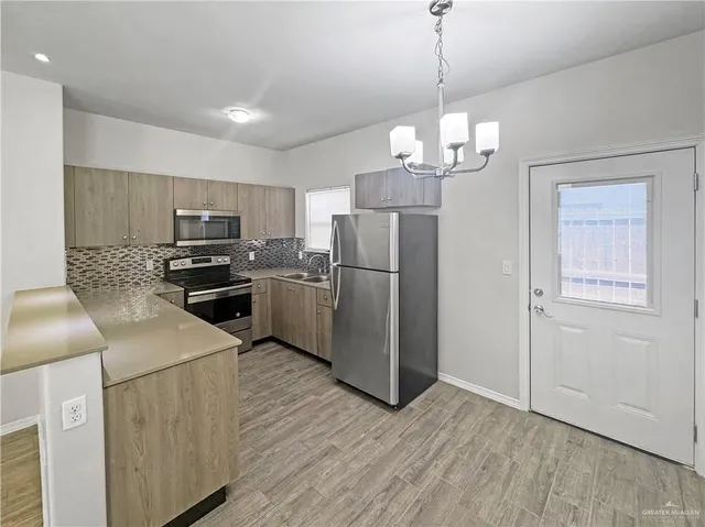 a kitchen with stainless steel appliances granite countertop a refrigerator a stove top oven a sink and dishwasher