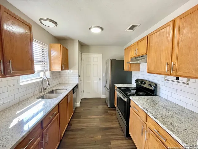 a large kitchen with granite countertop a sink and a stove