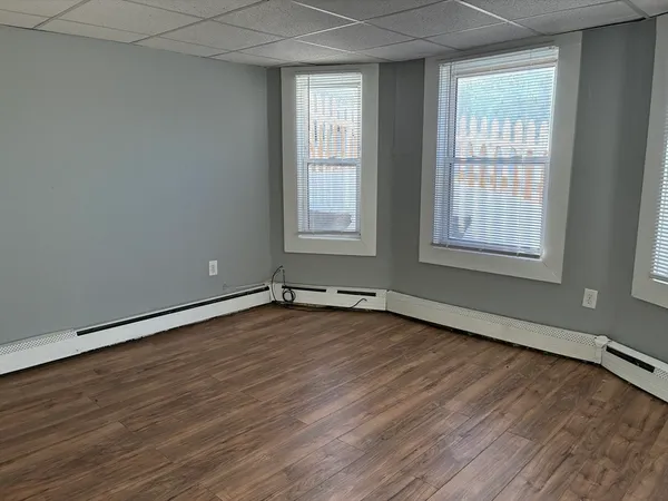 an empty room with wooden floor and windows