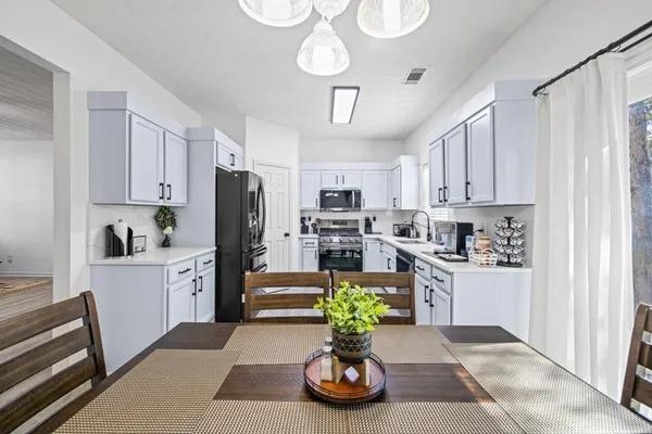 a kitchen with stainless steel appliances granite countertop a refrigerator a stove a sink dishwasher and white cabinets with wooden floor