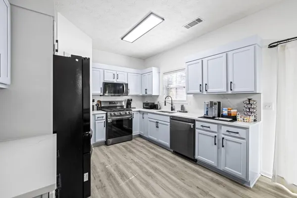 a kitchen with stainless steel appliances granite countertop a refrigerator a stove top oven a sink and dishwasher