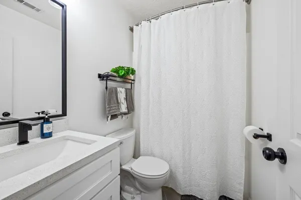 a bathroom with a granite countertop sink toilet and mirror