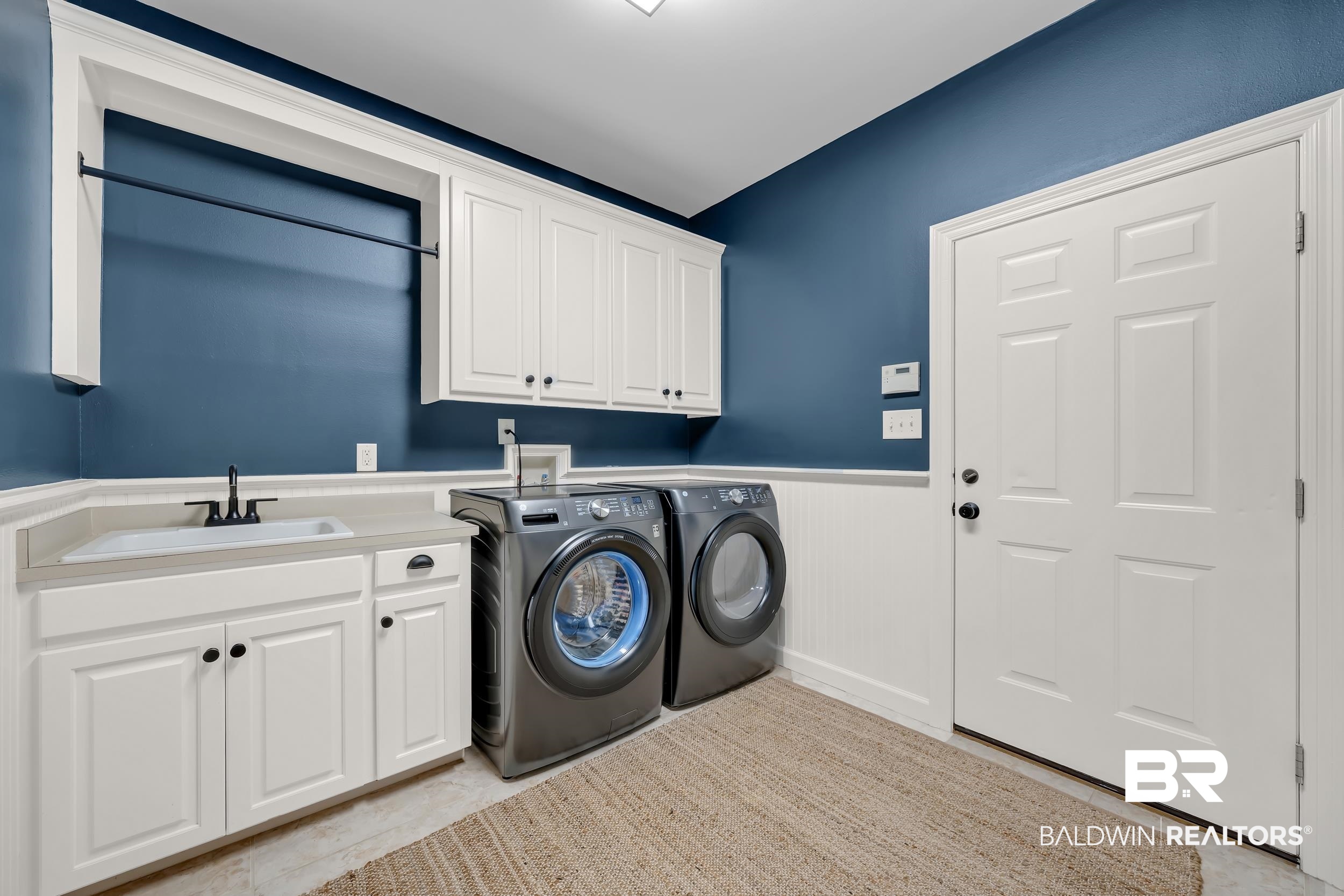 8137 Pine Run Daphne, AL 36527 - Photo 40 of 67 Laundry area featuring white cabinetry, a built-in sink with a black faucet, and a hanging rod