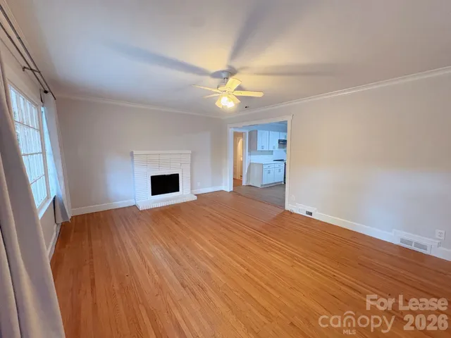 wooden floor in an empty room with a fireplace and a window