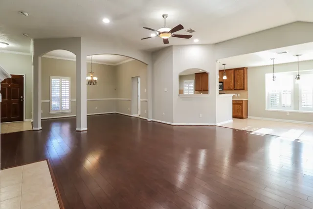 an empty room with wooden floor and a ceiling fan