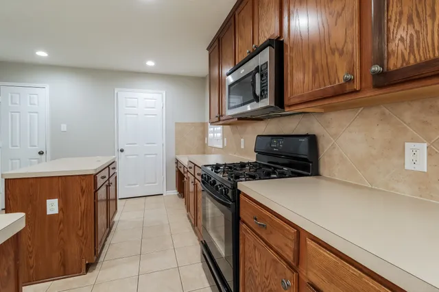 a kitchen with stainless steel appliances granite countertop a stove a sink and a microwave