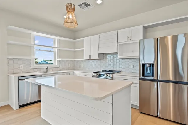 a kitchen with a sink a center island cabinets and a window