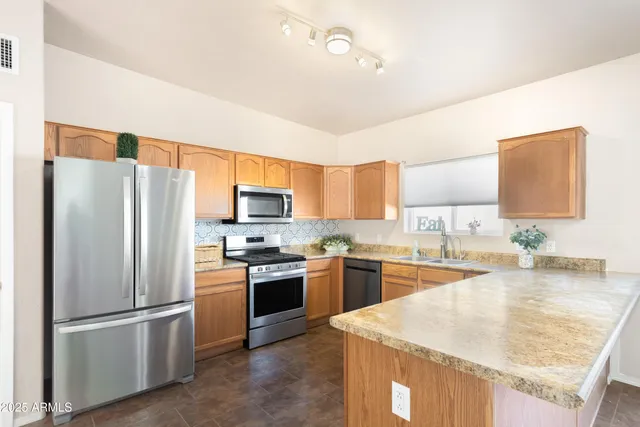 a kitchen with stainless steel appliances granite countertop a refrigerator stove microwave and sink