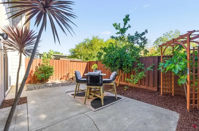 a view of a patio with table and chairs and potted plants with wooden fence