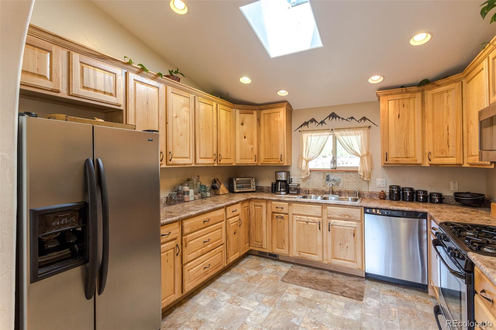 32147 Sylvan Road Golden, CO 80403 - Photo 12 of 27 a kitchen with stainless steel appliances granite countertop a refrigerator a sink dishwasher a stove and white cabinets with wooden floor