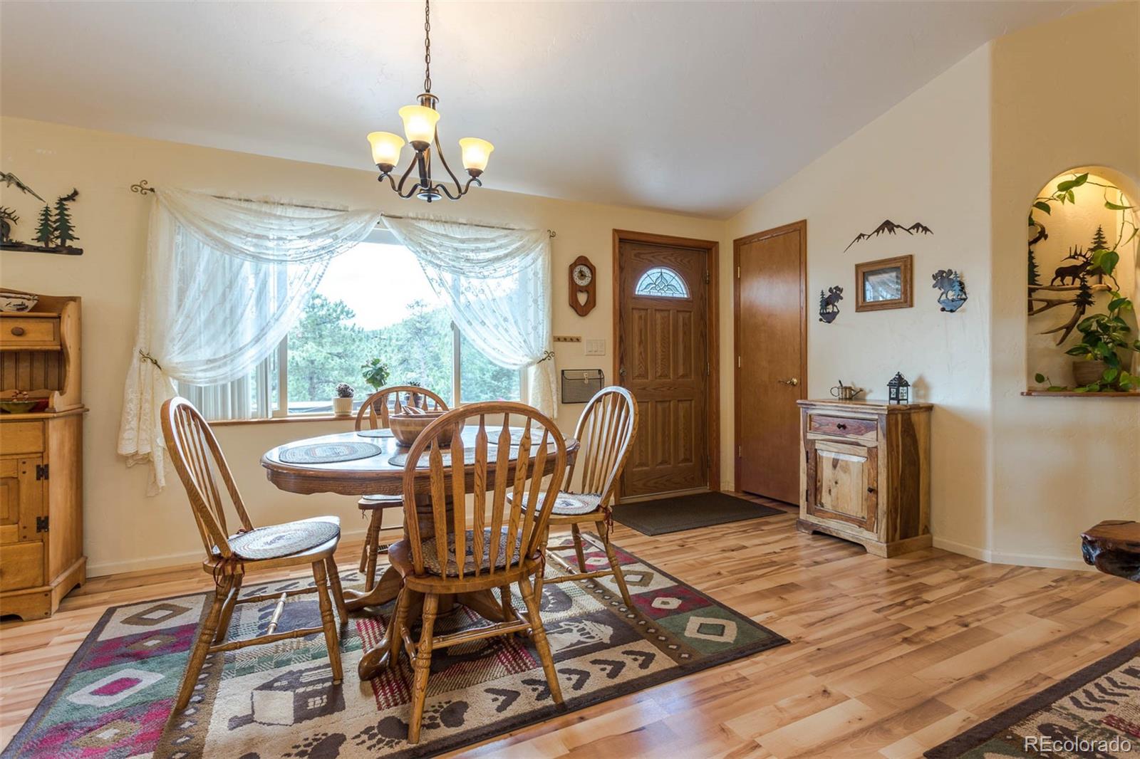 32147 Sylvan Road Golden, CO 80403 - Photo 6 of 27 a dining room with furniture a chandelier and wooden floor