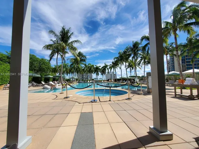 a view of a swimming pool with lounge chair and palm trees