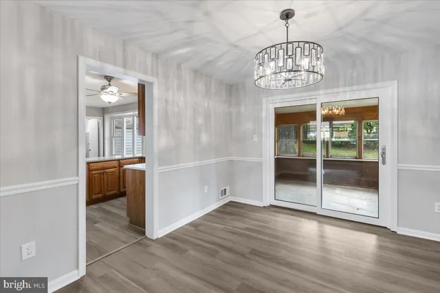 an empty room with wooden floor and a kitchen