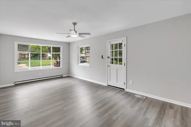 an empty room with wooden floor chandelier and windows