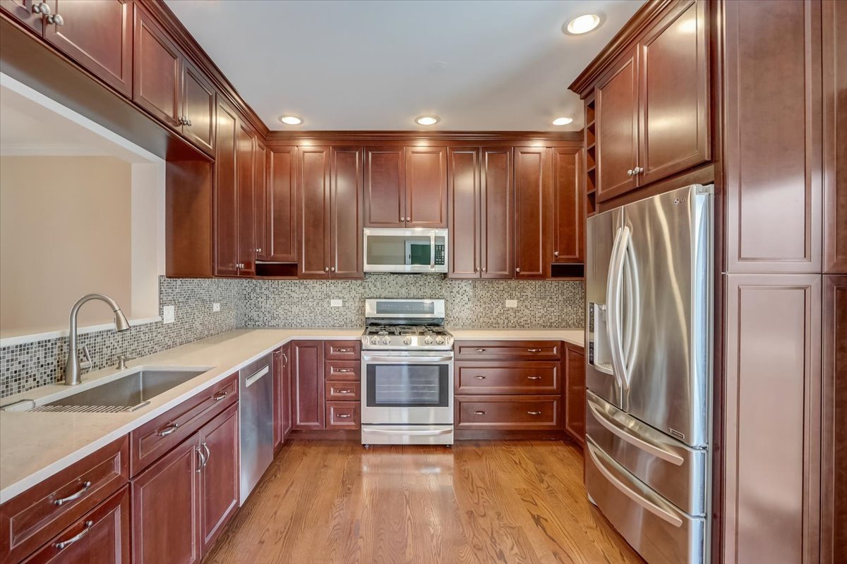 3372 Ravinia Circle Aurora, IL 60504 - Photo 13 of 39 a kitchen with stainless steel appliances granite countertop a refrigerator a sink dishwasher a stove with wooden cabinets and floor