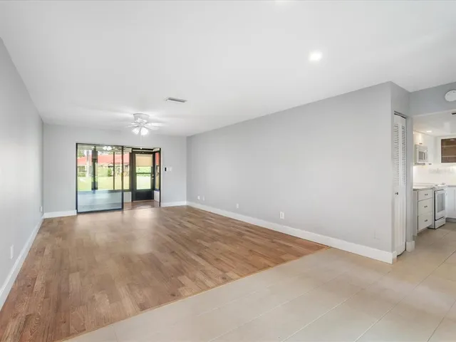 an empty room with wooden floor fan and windows