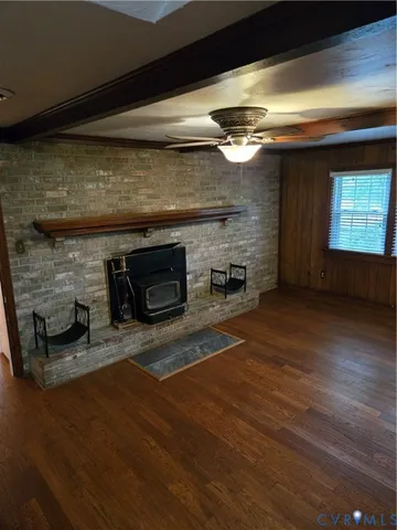 a view of an empty room with wooden floor fireplace and a window