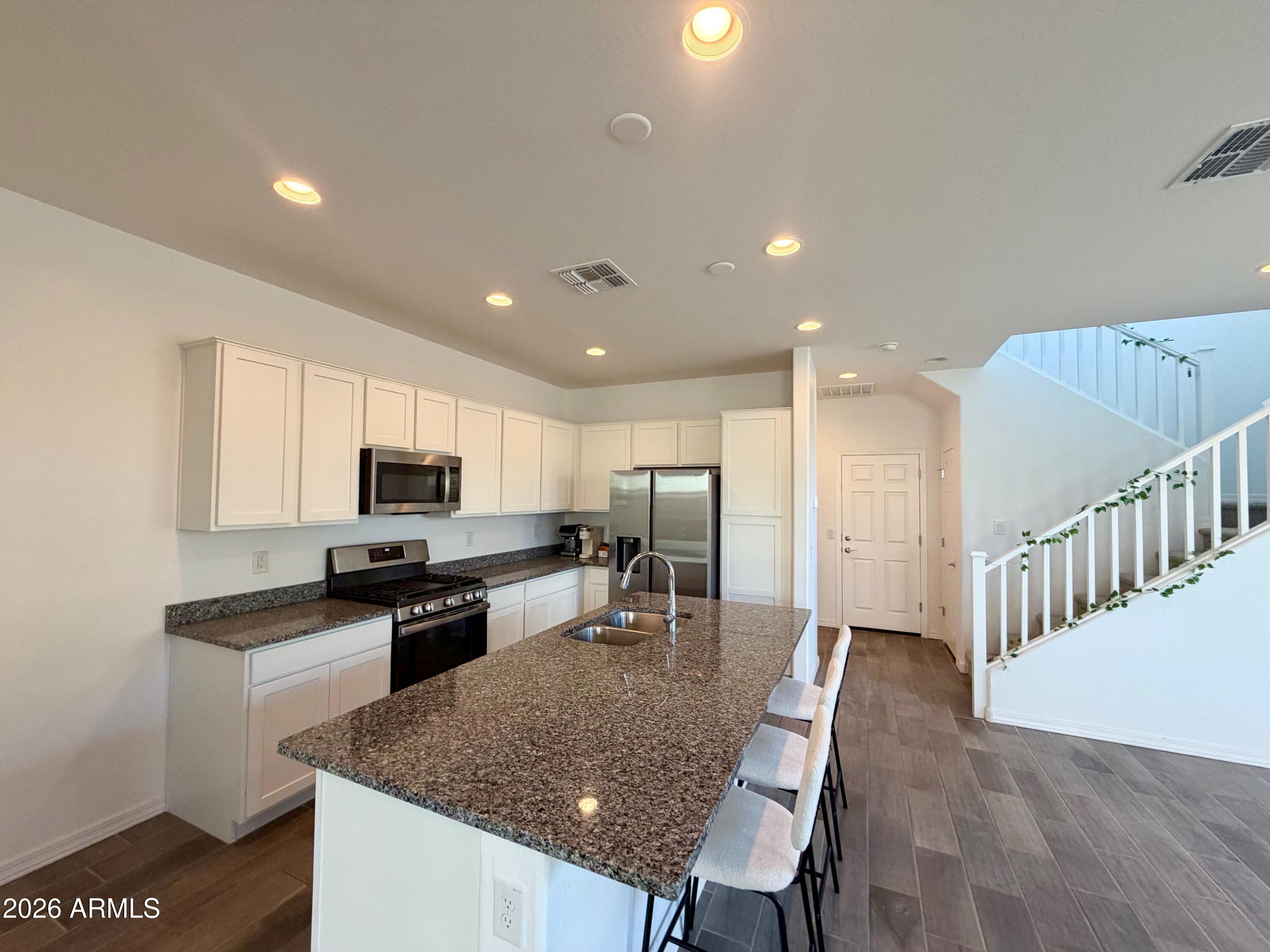 a kitchen with kitchen island granite countertop a stove a sink a microwave a dining table and chairs