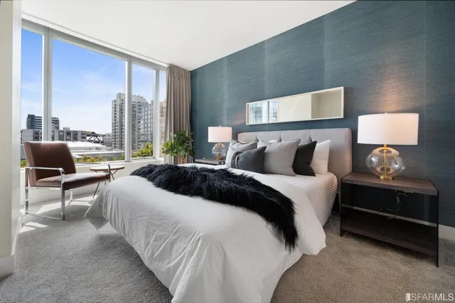 a bedroom with a bed a painting on the wall and a large window